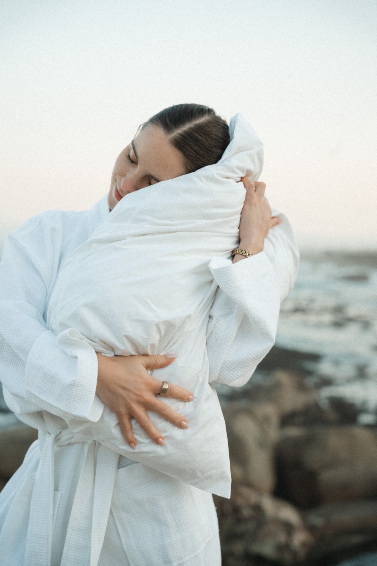 Guest smiling while hugging a white Dover pillow in a waffle robe