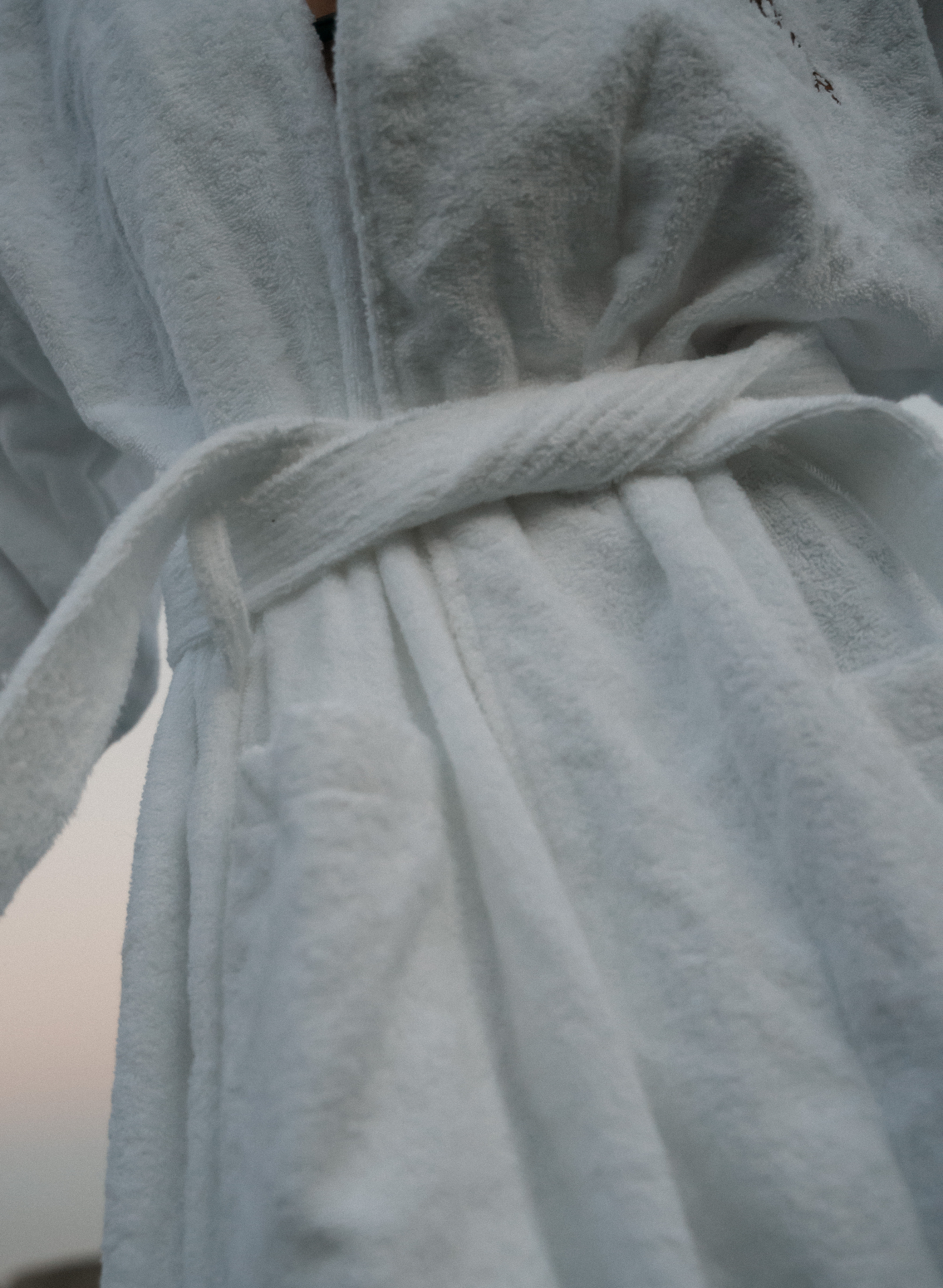 Close-up of a white robe belt knotted at the waist