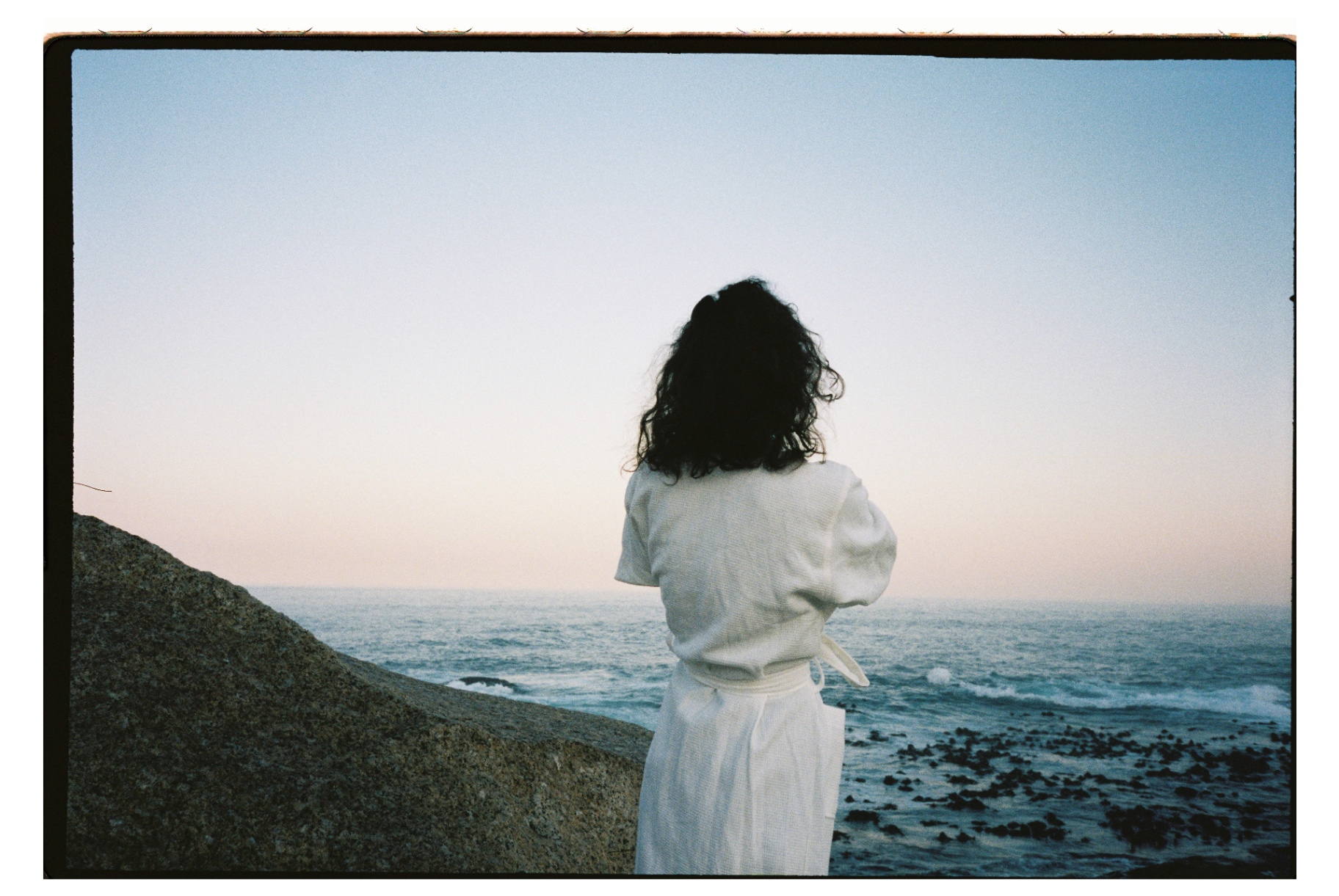 Guest in a white Dover waffle robe looking out to sea