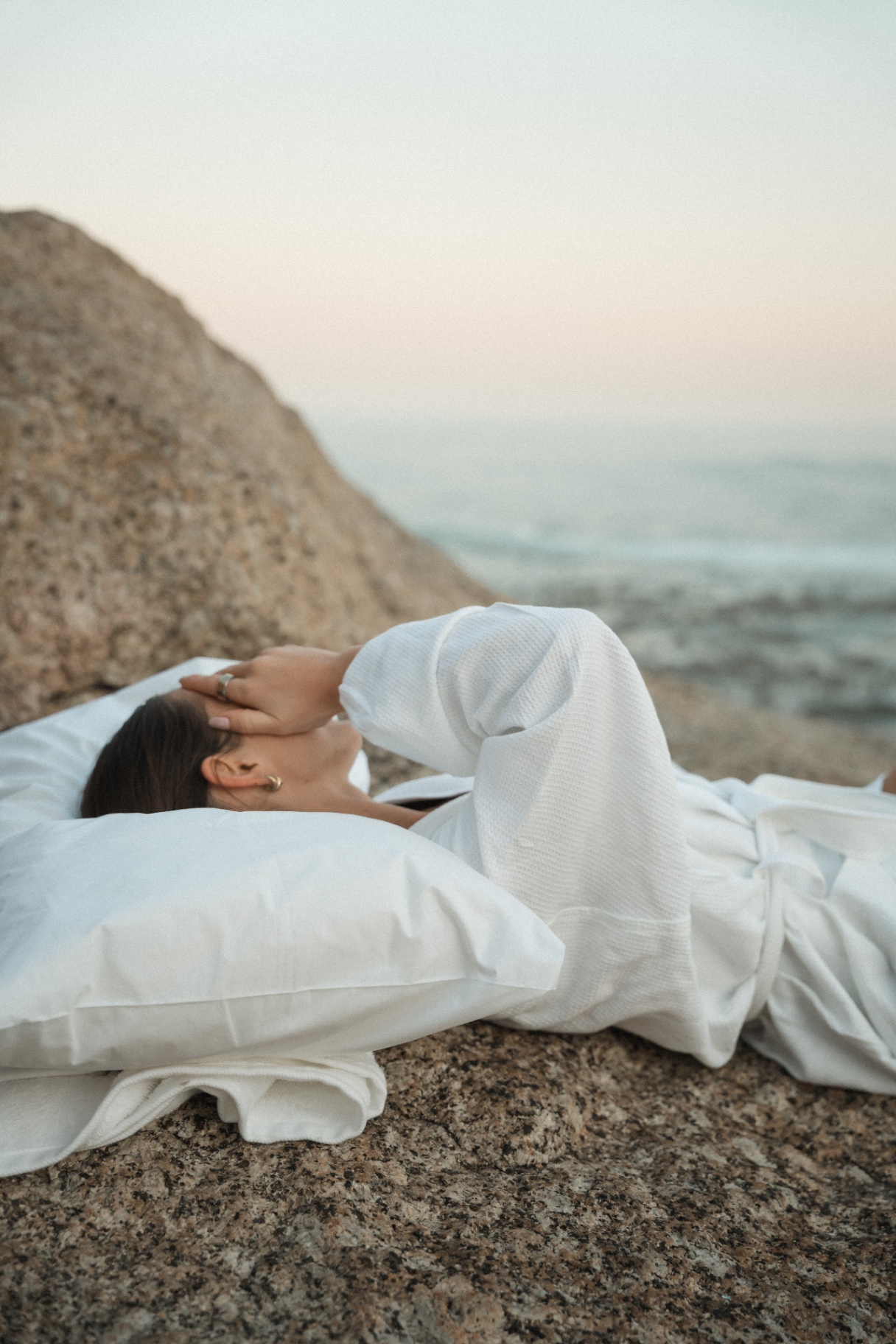 Guest resting on a Dover pillow against a coastal rock